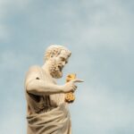 A statue of St. Peter with symbolic keys set against a clear blue sky.